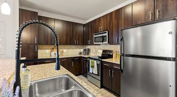 A kitchen with a stainless steel refrigerator and a sink with a faucet.