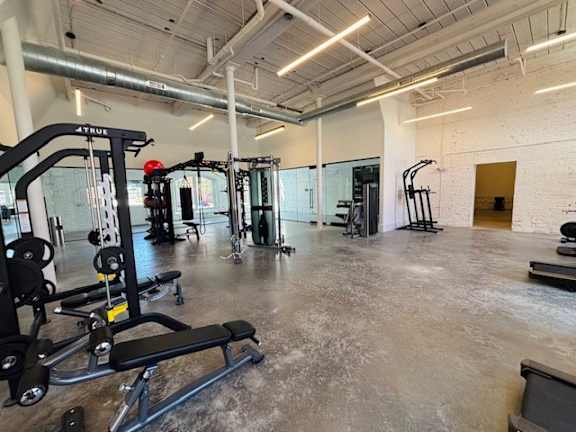 A gym with a variety of equipment including a weight bench, a leg press machine, and a squat rack.