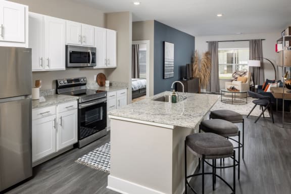 a kitchen with white cabinets and a large island with granite countertops at Fairview Springs in Covington, GA, 30016