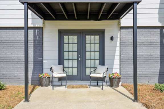 the front porch of a house with two chairs and a door at The Brookwood, Homewood, AL, 35209