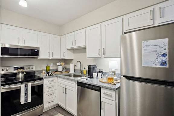 a kitchen with stainless steel appliances and white cabinets at The Brookwood, Alabama, 35209
