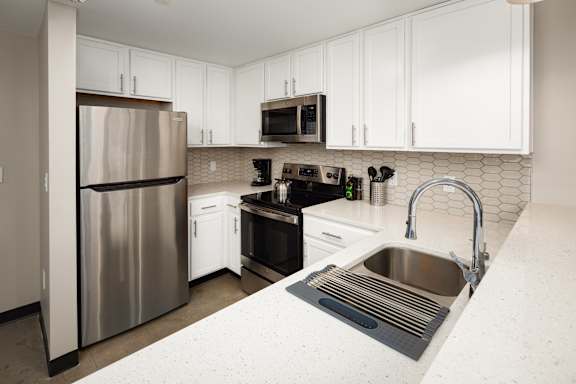 a kitchen with white cabinets and stainless steel appliances at Tower on Tenth Apartments, Birmingham, AL
