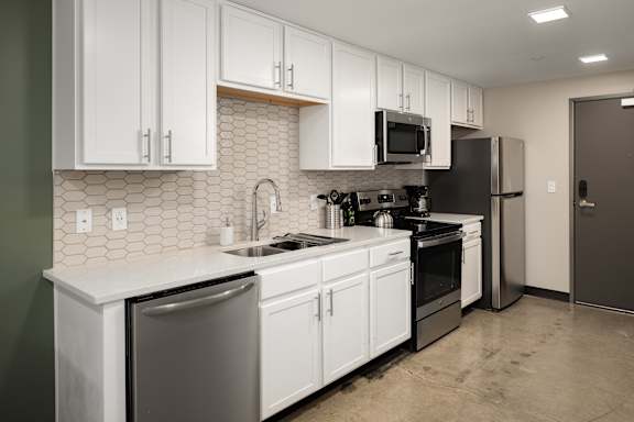 a kitchen with white cabinets and black appliances at Tower on Tenth Apartments, Birmingham 35205