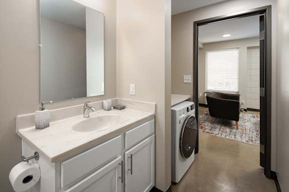 a bathroom with a sink and a washer and dryer at Tower on Tenth Apartments, Birmingham, Alabama