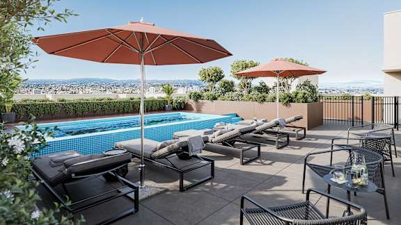 A patio with a pool and chairs.