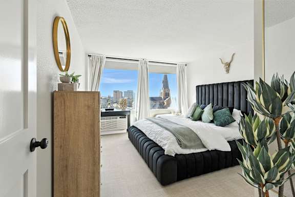A bedroom with a large bed and a view of the city.