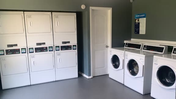 a row of washing machines and dryers in a laundry room