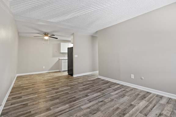 an empty living room with wood flooring and a ceiling fan