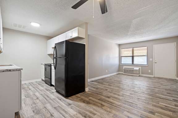 an empty kitchen and living room with a refrigerator and a window