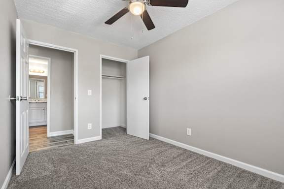 an empty living room with a ceiling fan and a door to a bathroom