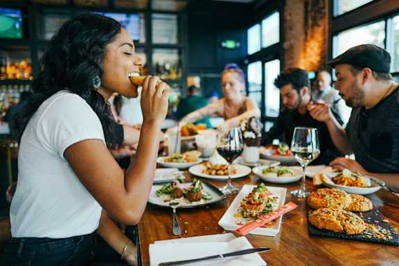 A woman is eating in a restaurant with a group of people.