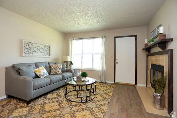 A living room with a grey couch and a glass coffee table.