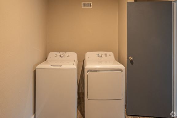 Two white front load washing machines in a laundry room.
