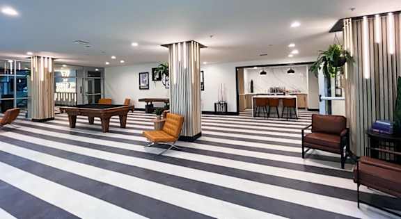 A black and white striped floor in a room with a long table and chairs.