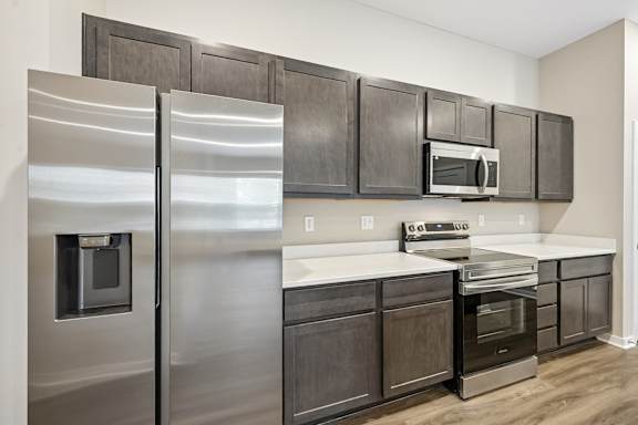 A modern kitchen with dark wood cabinets and stainless steel appliances.