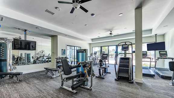A spacious gym with a variety of equipment including treadmills, stationary bikes, and weight machines.