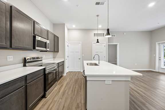 A modern kitchen with dark brown cabinets and white countertops.