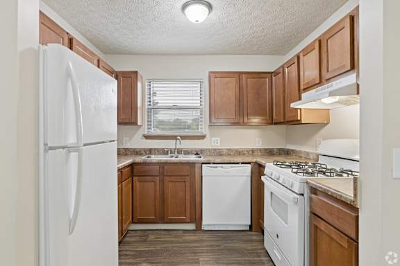 A kitchen with white appliances and wooden cabinets.
