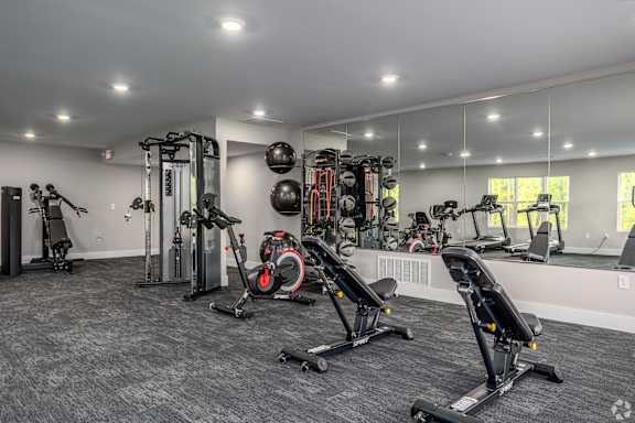 A spacious gym with a variety of equipment including treadmills, stationary bikes, and weight machines.