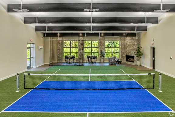 A tennis court is set up indoors with a net and two chairs.