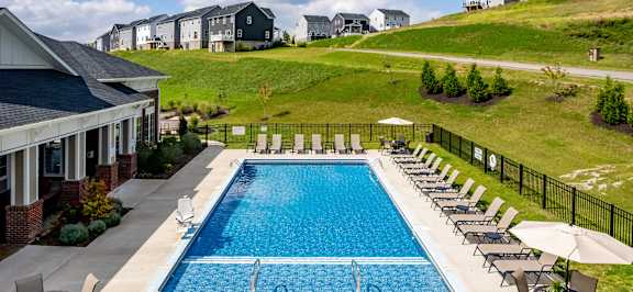 a swimming pool in front of a house with a hill behind it at The Flats at Summit Station, South Park, Pennsylvania