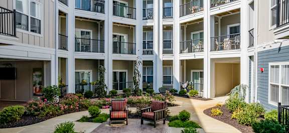 a courtyard with benches and plants in front of a building at The Flats at Summit Station, South Park, Pennsylvania