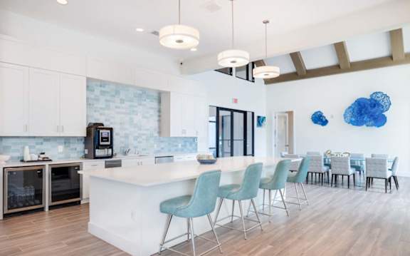 A kitchen with a white island and blue chairs.