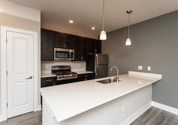 A kitchen with a white countertop and dark cabinets.