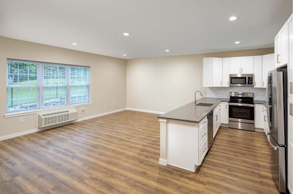 an empty kitchen with an island and stainless steel appliances at The Point at Gateways, New Jersey
