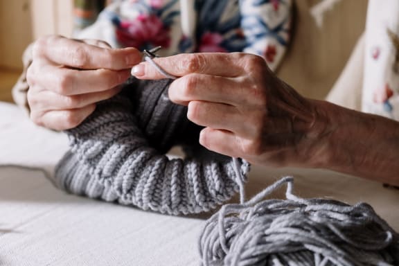 a woman knitting a sock on a table