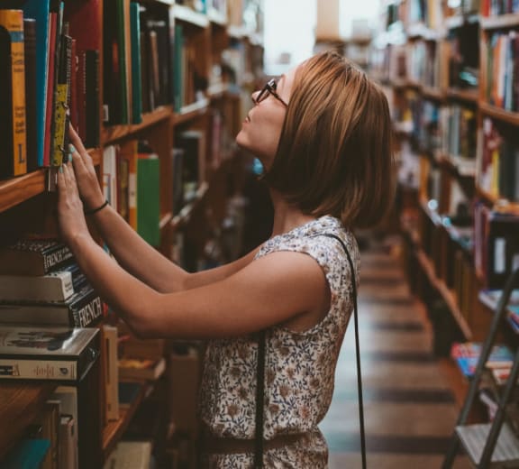 Woman looking at books at Oceanwood Apartments, Lompoc, 93436