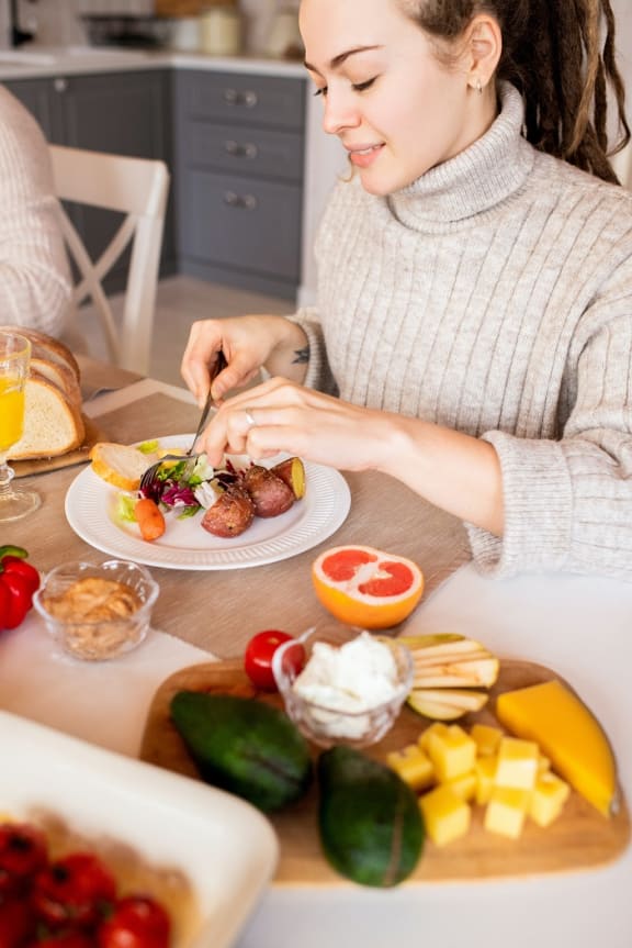 a woman sitting at a table eating a plate of food