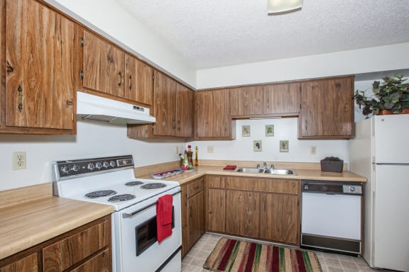 Wooden cabinets and white appliances at Cloverset Valley Apartments, Kansas City, Missouri
