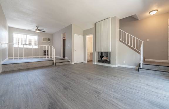 A spacious living room with a fireplace and a staircase.
