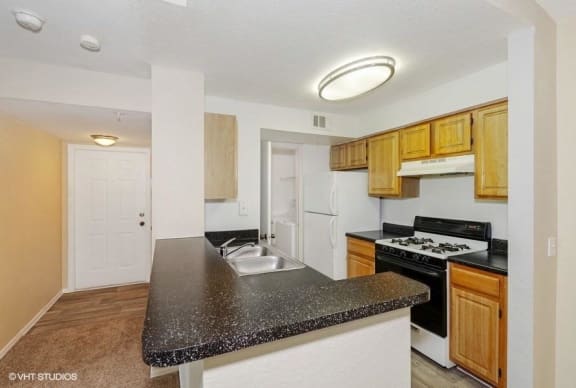Kitchen with Breakfast Bar Black Counters and Blonde Cabinets