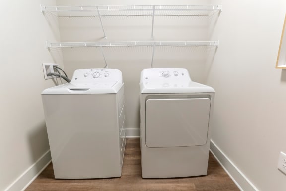 a washer and dryer in a room with a white wall and a shelf at Annandale Apartment Homes, Murfreesboro, TN, 37128