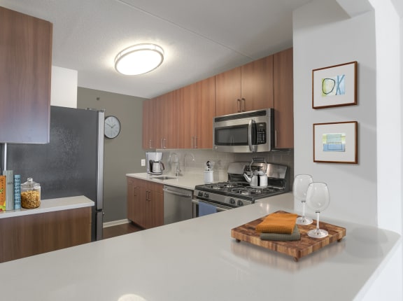 A kitchen with a white counter top and wooden cabinets at 10 West Apartments, Long Beach, NY, 11561