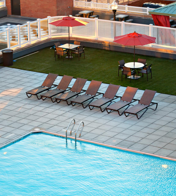 A pool with a few chairs and umbrellas at 10 West Apartments, Long Beach