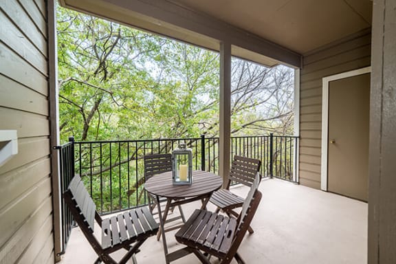 a patio with a table and chairs and a door that leads to a balcony at High Oaks, Austin, 78759