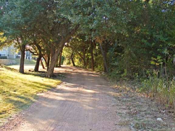 a dirt road with trees on both sides at Monterey Ranch, Austin, TX, 78749