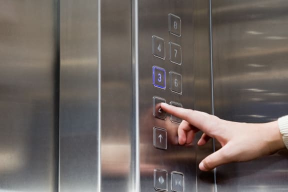 person pushing elevator button-Senior Living at Cambridge Heights Apartments, St. Louis, MO--Senior Living at Cambridge Heights Apartments, St. Louis, MO