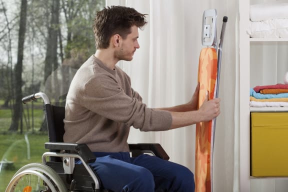 man in a wheelchair grabbing an iron board