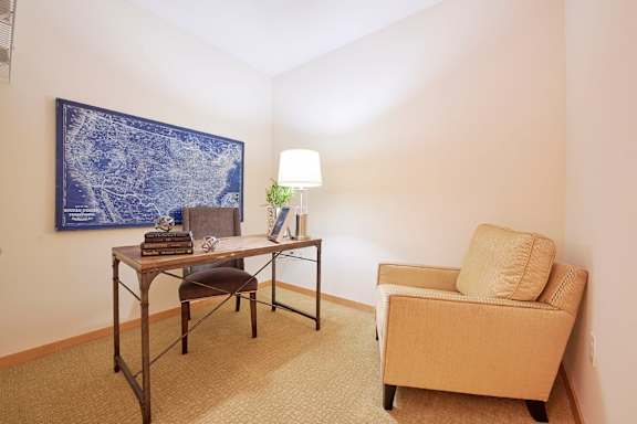 A room with two chairs, a table, and a painting on the wall.