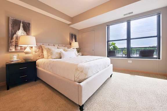 A bedroom with a large bed and a window overlooking a balcony.