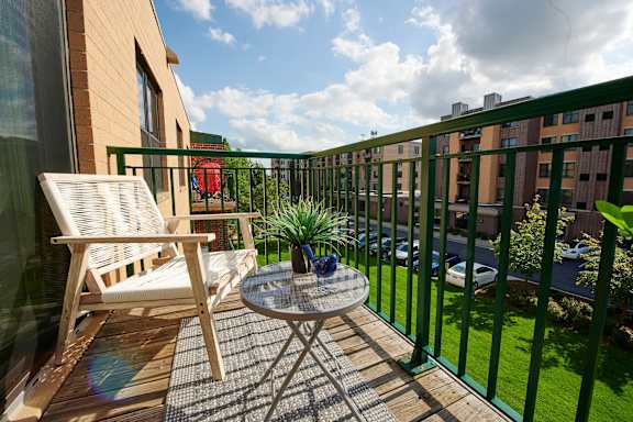 A balcony with a table and chair overlooking a green lawn.