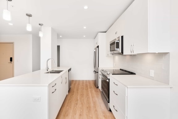 an all white kitchen with a stove and a microwave