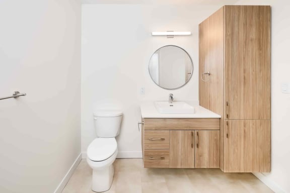 a bathroom with a toilet sink mirror and cabinets