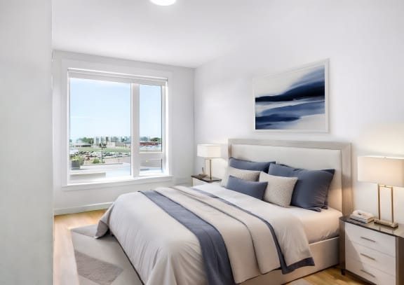a bedroom with a large window and a bed with blue and white pillows