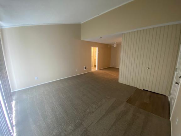 A living room with a carpeted floor and a doorway leading to another room.