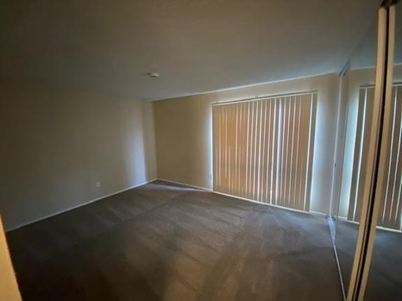 A room with a window covered by blinds and a wooden floor.